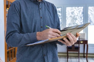 Inspector holding a notebook in his hand. Close-up of man's hands taking notes while standing