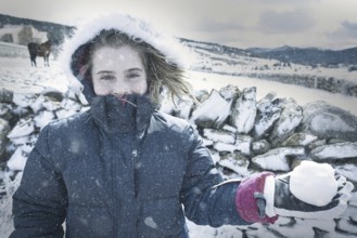 Blond kid girl playing with snow ball in winter
