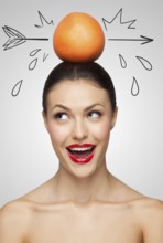Creative portrait of a beautiful smiling woman holding a red grapefruit pierced with a sketchy