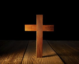 Christian wood cross on black and wooden background