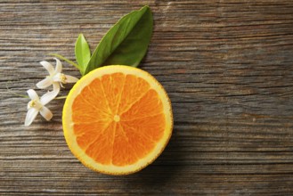 Cut half open orange fruit with orange flower on wooden table