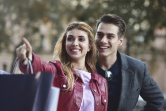 Beautiful couple with shopping bags is talking and smiling while doing shopping in the mall focus