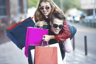 Happy couple shopping together and having fun. Boyfriend carrying his girlfriend on the piggyback