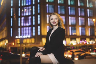 Portrait of Beautiful young woman in black on a background of a night city. night life