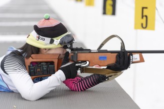 Sportswoman biathlete Yu Seolhee South Korea rifle shooting in prone position. Biathlete in