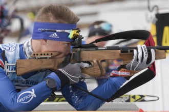 Sportsman biathlete rifle shooting, aiming, reloading rifle in prone position. Junior biathlon