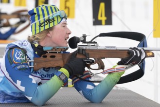 Sportswoman biathlete Legostaeva Anastasia rifle shooting in prone position. Biathlete in shooting