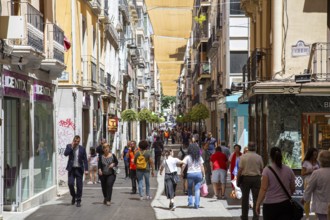Granada, Spain, May 27, 2019: People walking in a charming narrow shopping street in the historic
