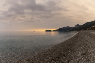 A view of the stone pebble beach and clear water at Letojanni on Sicily at sunsest