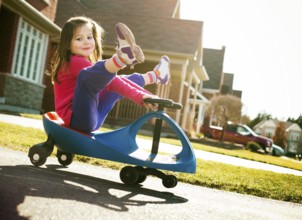 Small girl is having fun riding his toy on the street, Toronto, Canada, North America