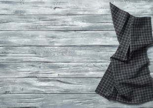 Gray wooden table with balck and white dark linen kitchen towel or textile napkin flat lay. Dark