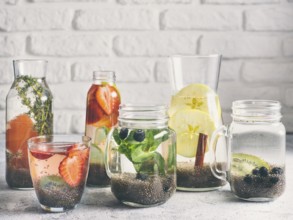 Different chia water in glass on gray background. Chia infused detox water with berries, fruits and