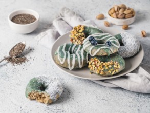 Vegan doughnuts with chia seeds topped with healthy spirulina glaze with pistachio, desiccated
