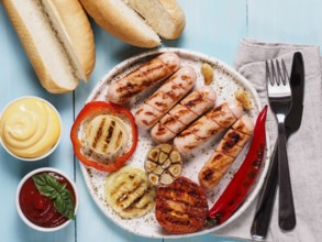 Top view of chicken homemade sausages, buns bread, sauces ketchup and mustard on blue wooden
