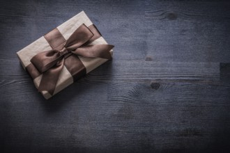 Present box-container with brown tied bow on vintage wooden board