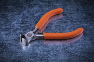Insulated electric metal nippers on metallic background electricity concept