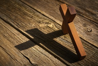 Christian cross on wood over wooden background vintage with shadows