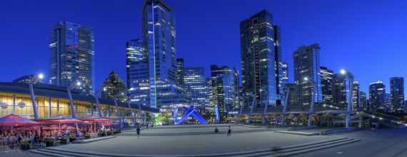 Night view of a modern city with illuminated skyscrapers and a sculpture in the centre, Vancouver,