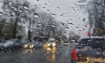 Melted snow and rain drops on the windshield of a car. Blurred outdoor view, winter season sleet as