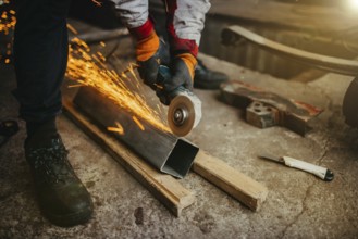 A worker grinding metal with sparks flying, wearing protective gloves