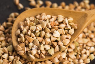 Buckwheat with a spoon on a wooden boards background