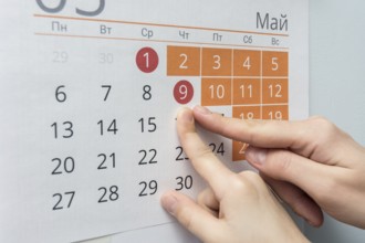 Child and adult hands indicate the date of May 9 wall calendar