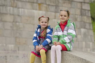 Two girls of four and six years of walking on the embankment of the river