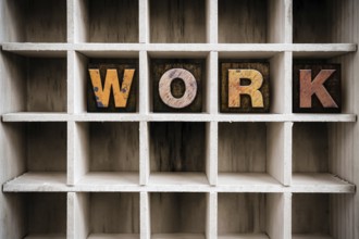 The word WORK written in vintage ink stained wooden letterpress type in a partitioned printer's