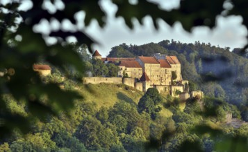 Burghausen Castle surrounded by green forests in the evening sun, view from the west, Burghausen,