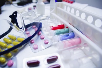 A lab table full of colorful pills and test tubes, accompanied by safety glasses