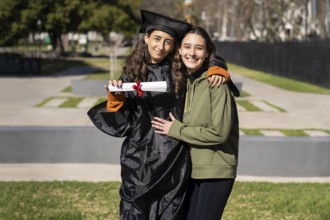 Recent graduate woman, dressed in cap and gown, showing off her degree celebrating with her family