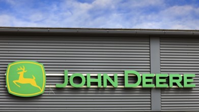 John Deere logo outside on building exterior with blue sky and clouds. Salo, Finland. June 25, 2023