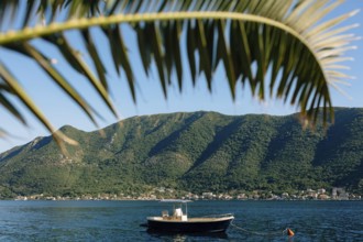 Fishing boat against the background of mountains on the blue water of the Bay of Kotor.