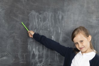 Schoolgirl shows on an empty school board. He is standing in the classroom at the chalkboard.