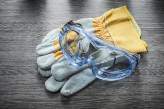 Construction gloves safety glasses on wooden board