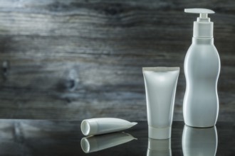 Tubes and sprayer skincare items on dark background