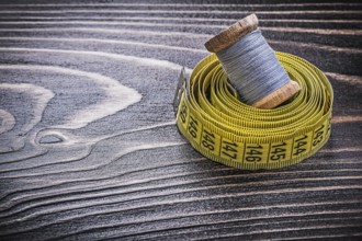 Vintage spool of thread tape measure on wooden board handicraft concept
