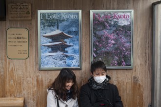 24.12.2017, Kyoto, Japan, Asia, A young couple sits at a bus stop in front of two posters
