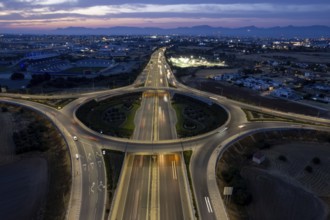 Aerial drone top view of a modern motorway junction roundabout with cars moving fast.