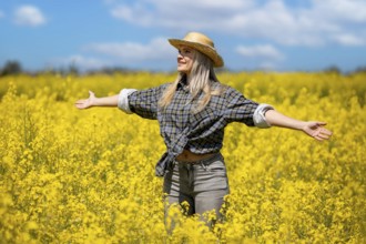 A cheerful woman is joyfully surrounded by a vast field filled with bright yellow flowers under a