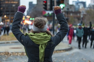 Young woman is raising her arms high while looking at the crowd during an ecological protest. Shot