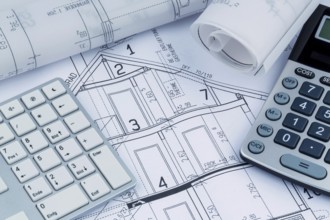 An architect's construction plan with a calculator. Symbolic photo for financing and planning a new