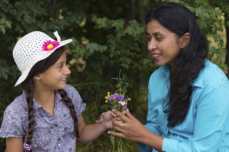Girl gives mum a bouquet of flowers she picked herself