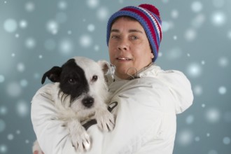 Woman with small dog in winter clothes in the snow