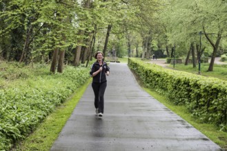 Jette, Brussels Capital Region Belgium, 04 24 2020 Attractive thirty year old woman jogging through