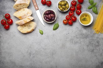 Food composition with sliced ciabatta, olives, olive oil, spaghetti, fresh basil, cherry tomatoes