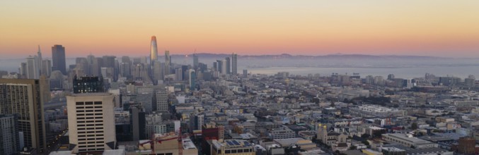 Orange hues seem to bounce off the tallest building as night comes to the San Francisco Bay area