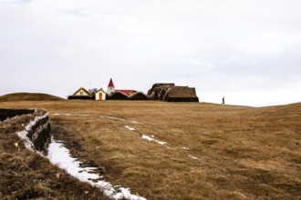An expansive landscape with a church and traditional buildings in the background, Iceland, Europe