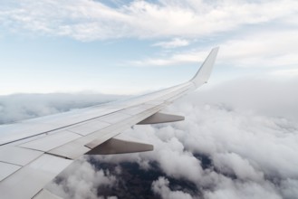 Wing of a flying airplane on clouds, view from the airplane window