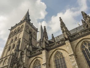 Impressive Gothic building with high towers and detailed decorations under a slightly cloudy sky,